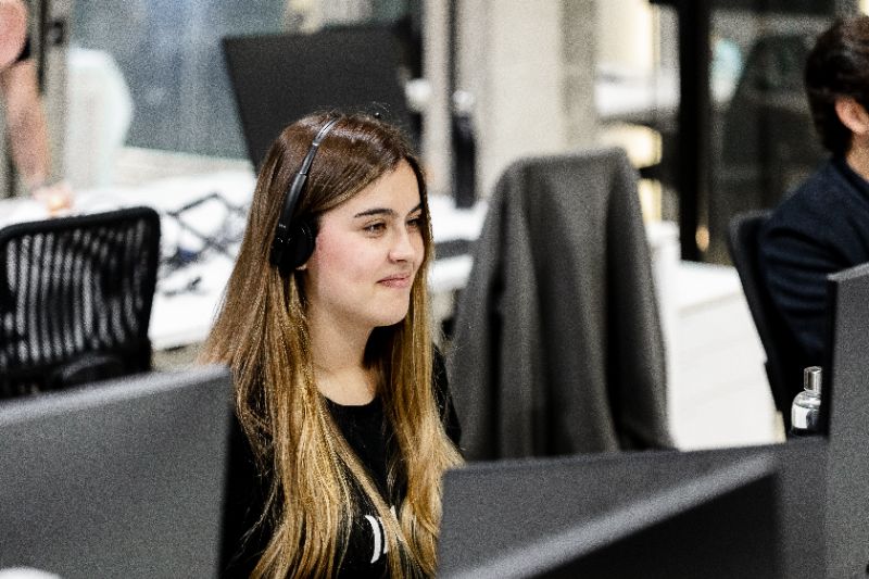 Mesa de escritório com checklist de implantação de T&D digital, laptop aberto com dashboard de LMS, caneta, café e notas organizadas