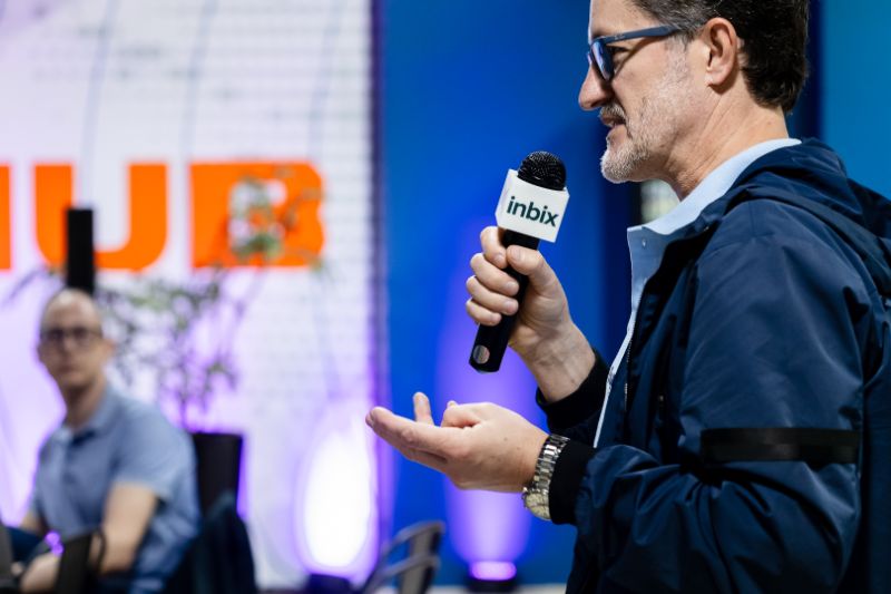 Colaborador interagindo com tutor virtual de inteligência artificial em ambiente corporativo moderno, com telas de computador exibindo dashboards de treinamento e gráficos de desempenho.