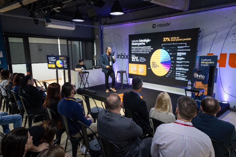 Equipe corporativa reunida ao redor de mesa com holograma de inteligência artificial no centro, mostrando conexão e inovação na cultura organizacional