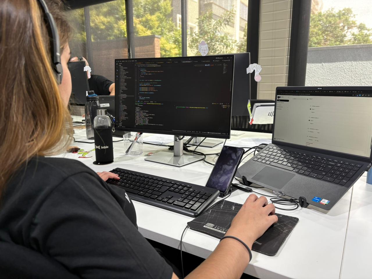 Gestor analisa feedback em painel digital de curso online com equipe colaborando ao fundo