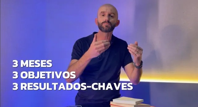 Gestor aponta para mural colorido com OKRs e gráficos de desempenho